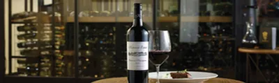 KatnnokEstateCabSavGlassFood Table set with a bottle and glass of Katnook Estate Cabernet Sauvignon